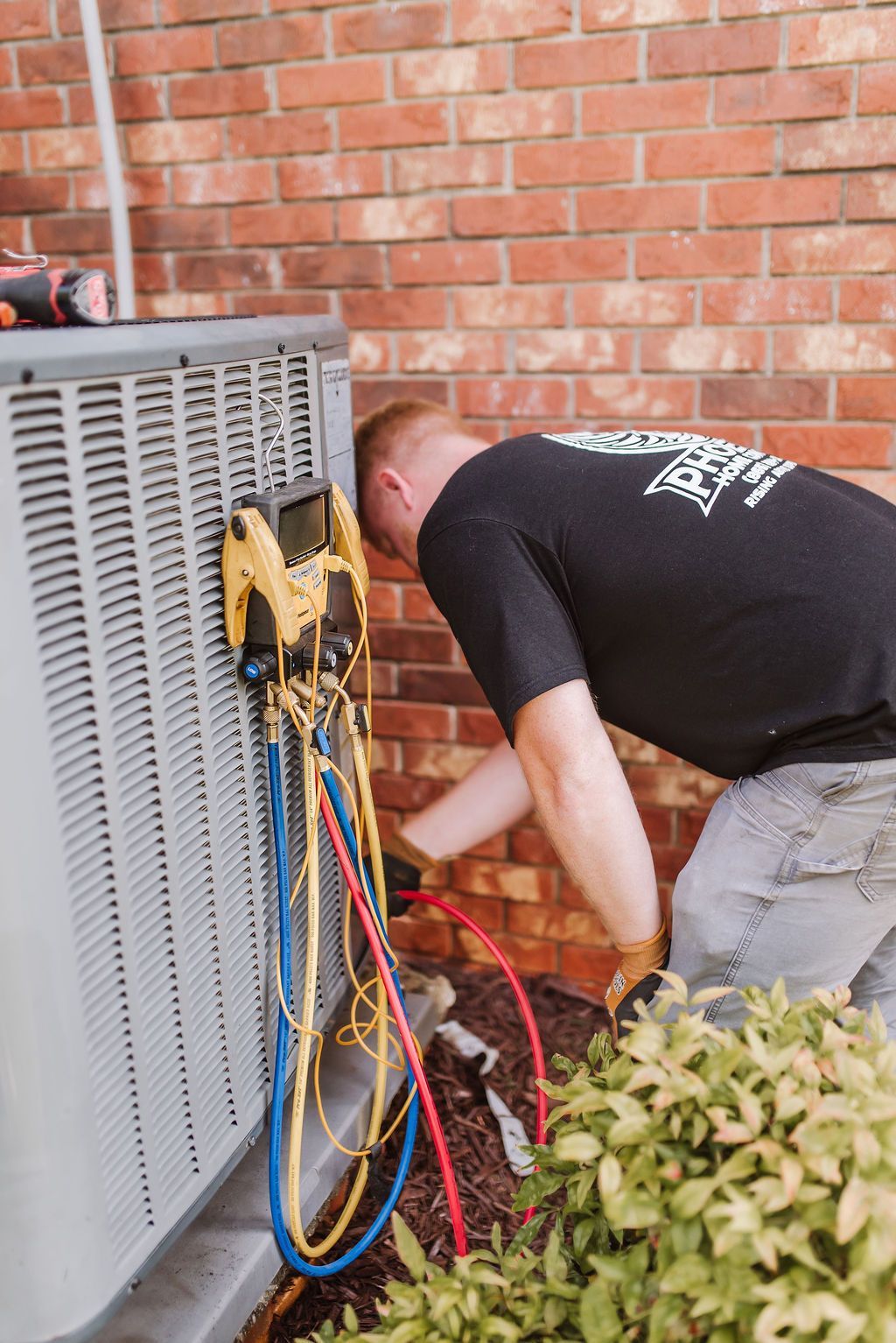 Tool bag with screwdrivers on an air conditioning unit in front of a house.