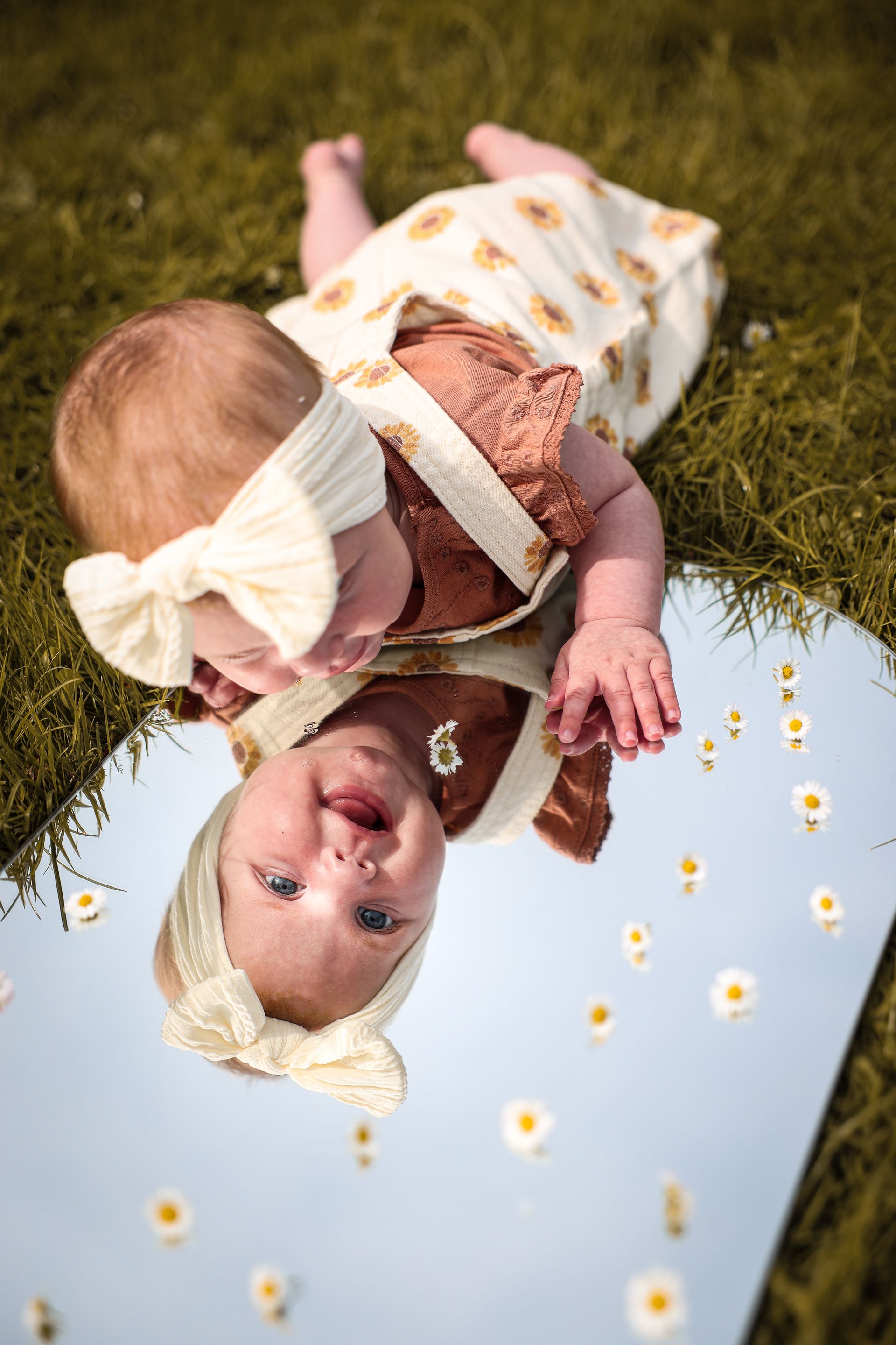 Baby in een bloemenoutfit ligt op het gras . Baby fotoshoot. Baby fotografie. Kinderfotograaf. Goedkope Kinderfotografie.