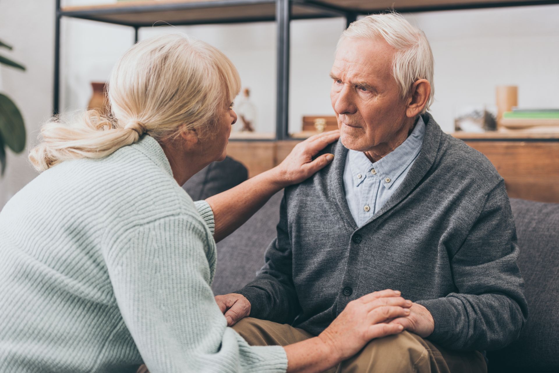 Retired couple holding hands and looking at each other at home.