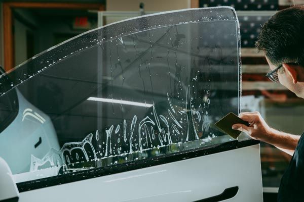 A person is polishing the hood of a red car.
