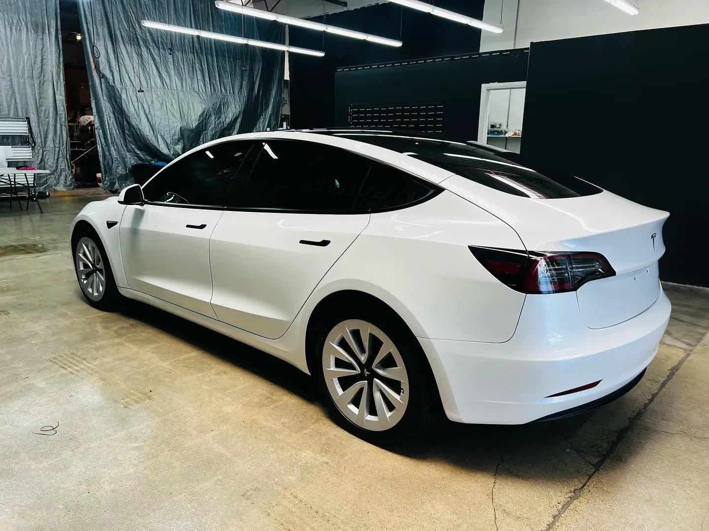 A man is cleaning a car with a sponge in a garage.
