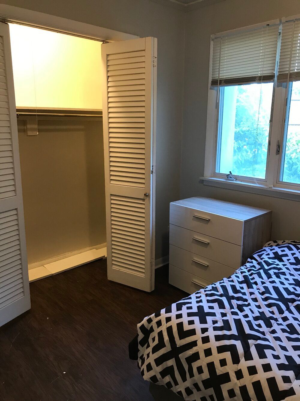 a bedroom with a bed a dresser and a closet