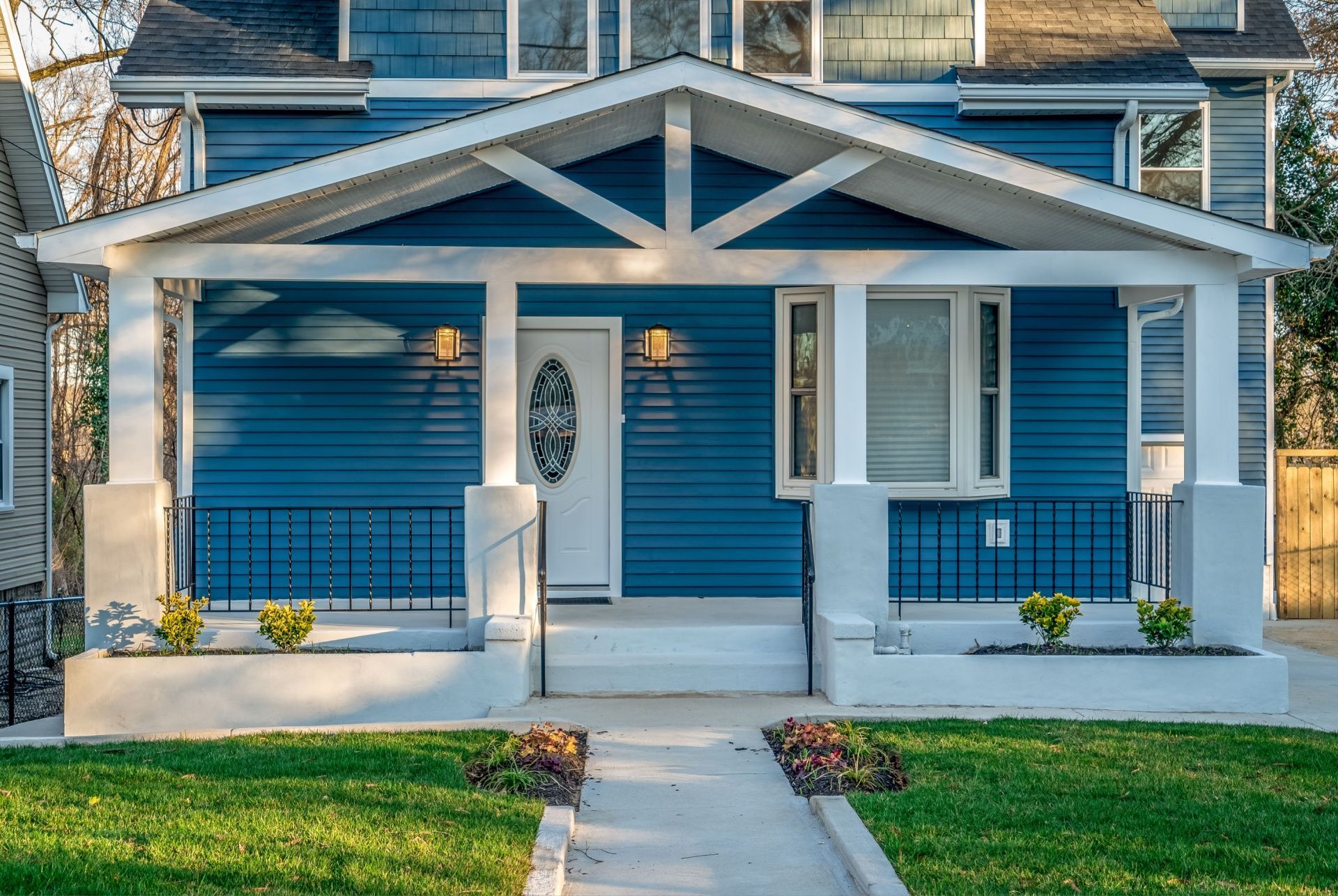 A blue house with a porch and a black roof.