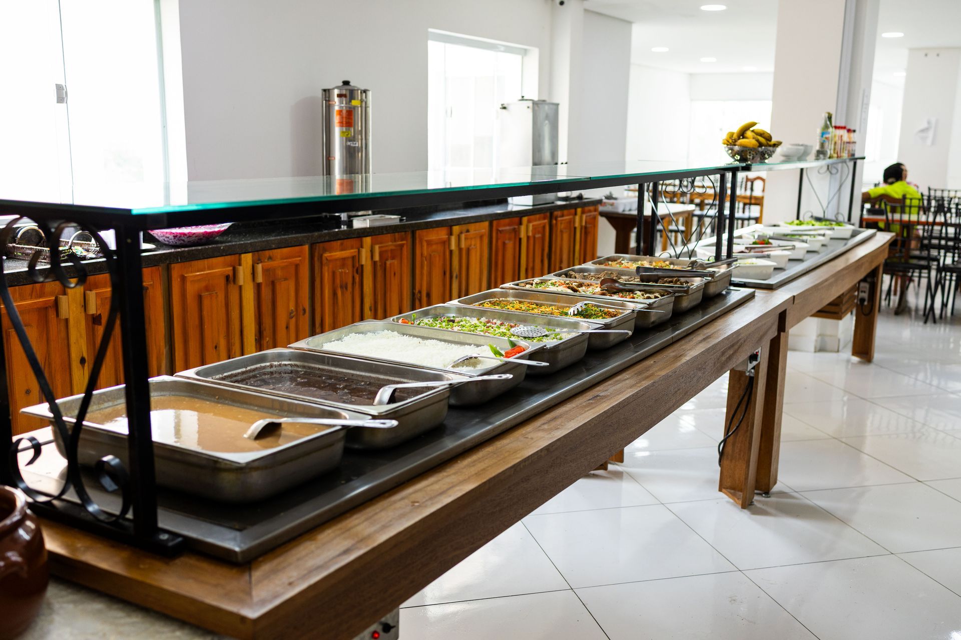 Apresentação de comida em estilo buffet com diversos pratos em uma área de refeições bem iluminada.