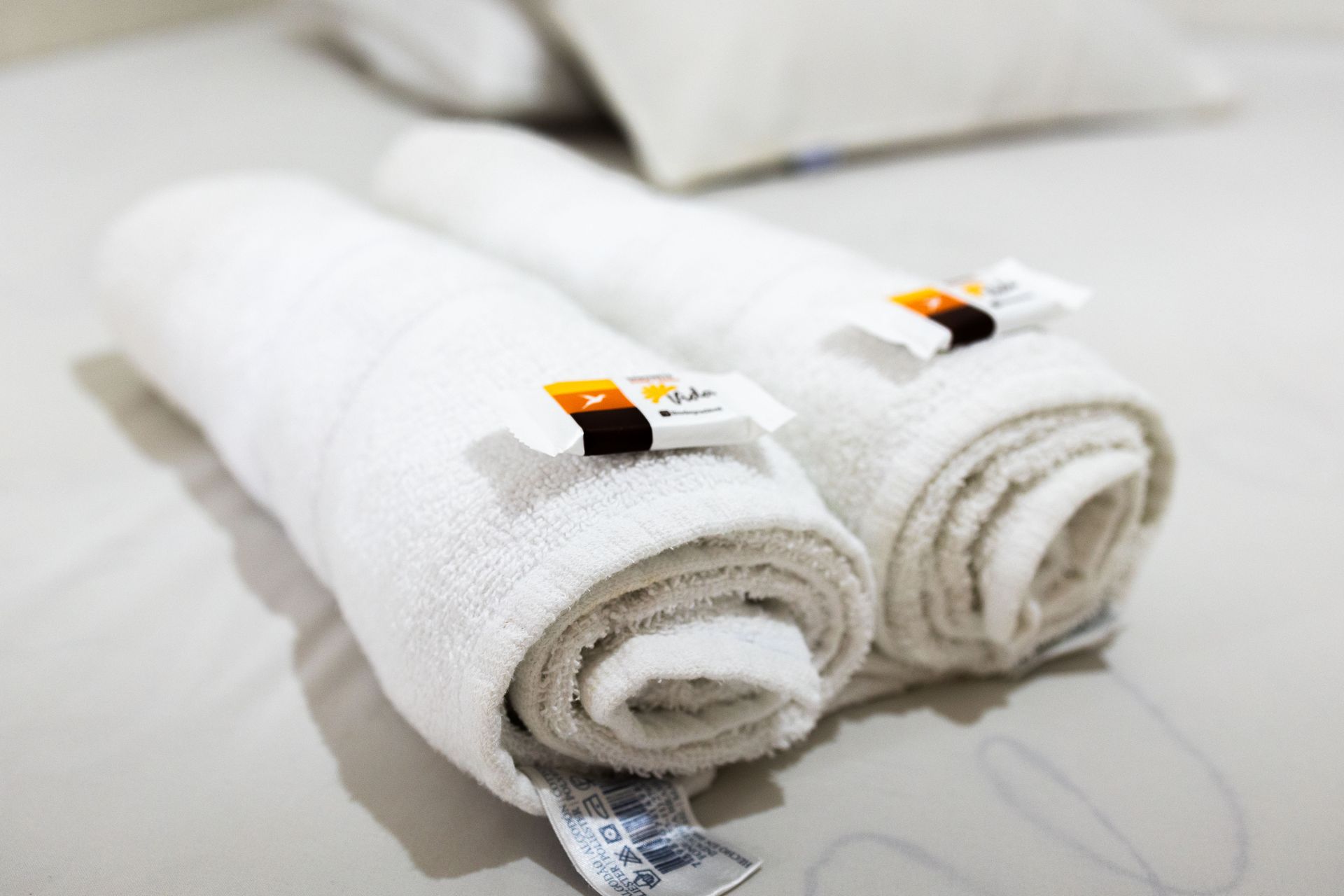 Toalhas brancas enroladas sobre a cama, cada uma com uma pequena barra de sabonete.
