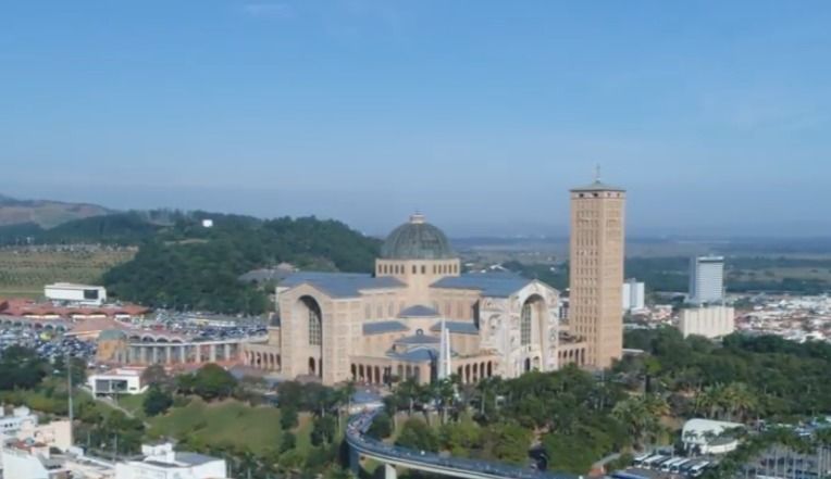 Basílica de Nossa Senhora Aparecida, Brasil, com cúpula, torre e paisagem circundante.