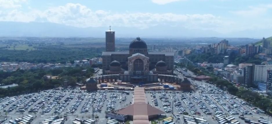 Vista aérea da Basílica de Nossa Senhora Aparecida, no Brasil, cercada por estacionamentos e pela paisagem urbana.