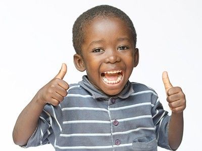 A smiling child in a blue and white striped shirt giving a double thumbs-up against a plain white background.