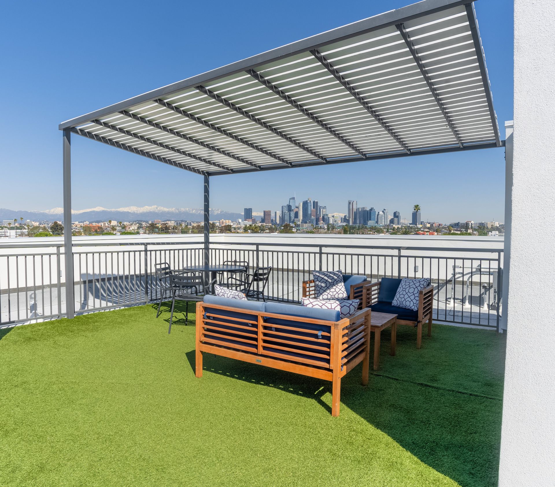 A rooftop deck with a couch and chairs under a canopy