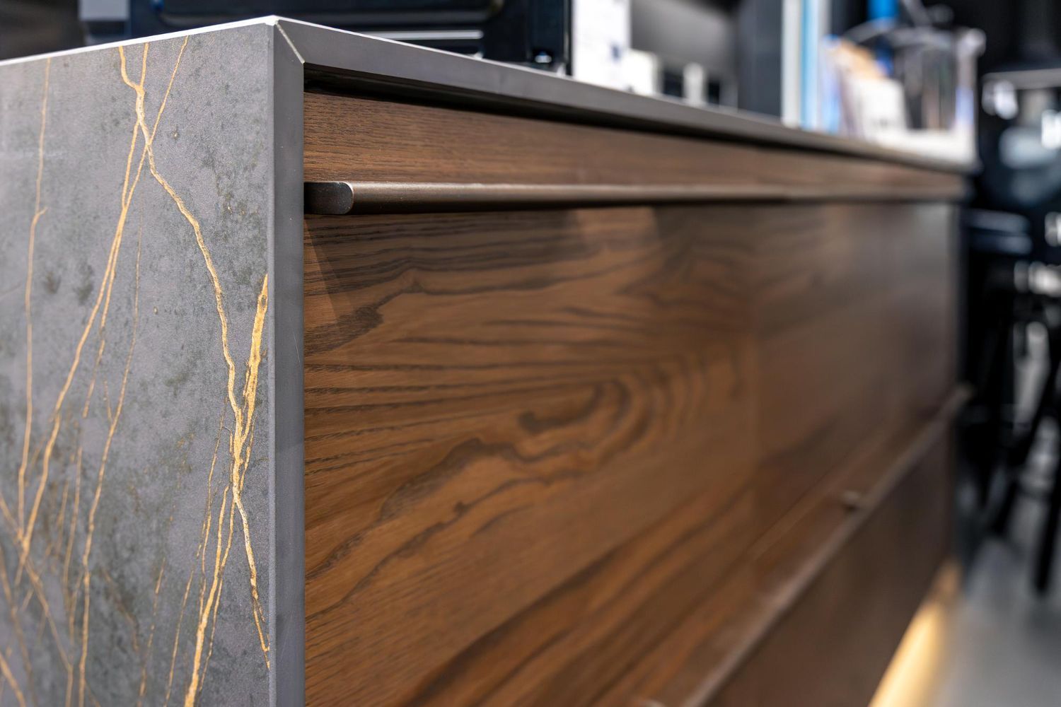 Primer plano de un moderno armario de madera con laterales de piedra gris oscuro y tirador de metal.