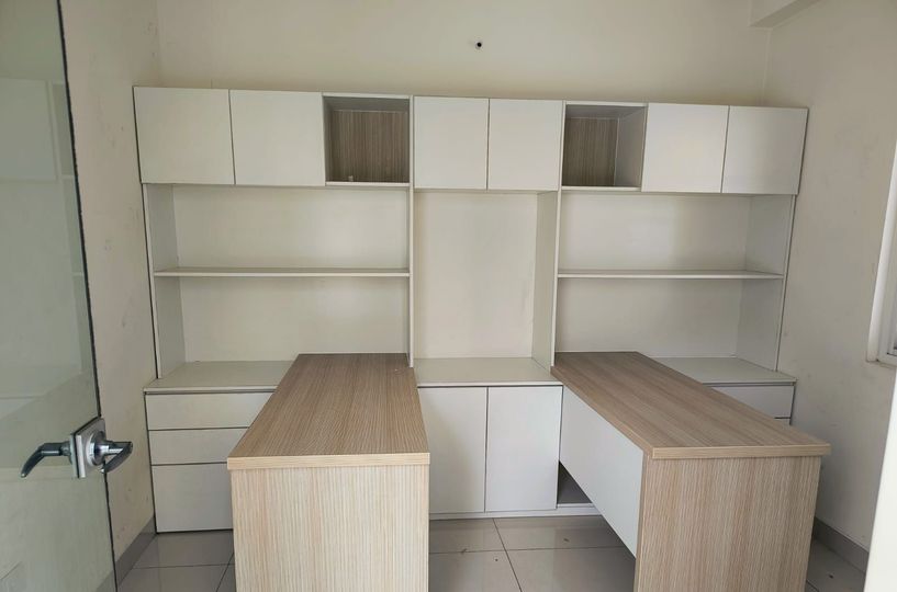 Oficina vacía con estanterías y armarios blancos empotrados, además de dos escritorios de madera orientados hacia la cámara.