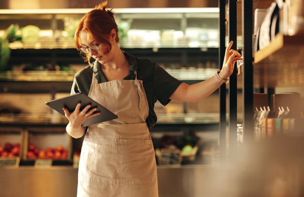 Une femme se tient debout dans une cuisine et tient une tablette.