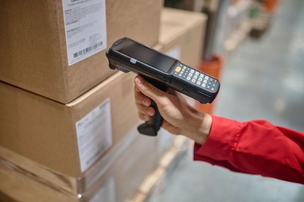 Une personne utilise un lecteur de codes-barres pour scanner une boîte dans un entrepôt.