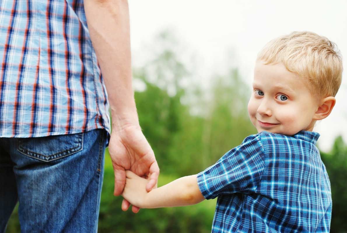 A child is holding a man's  hand