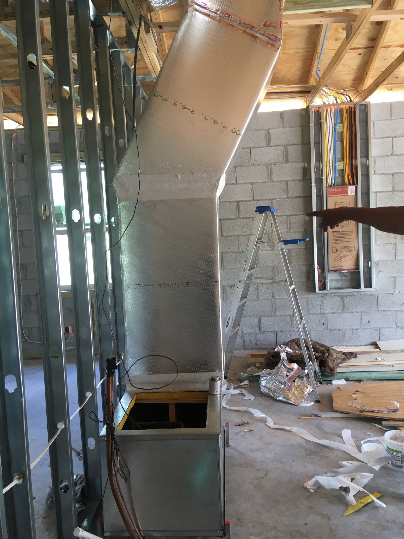 HVAC ductwork installation in a building under construction. Silver ducting connected to a unit.