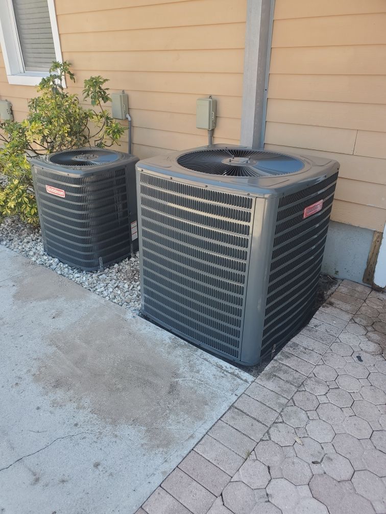 Two Goodman air conditioning units outside a tan building.