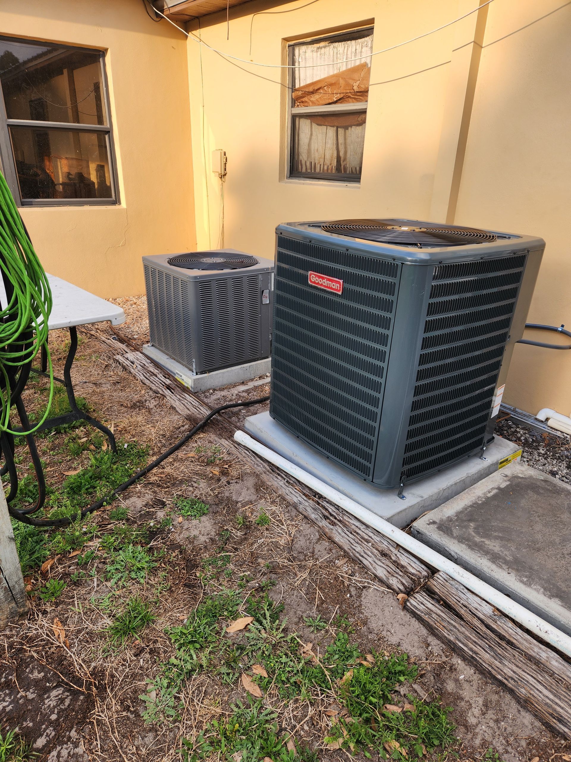 Two air conditioning units on concrete pads outside a building.