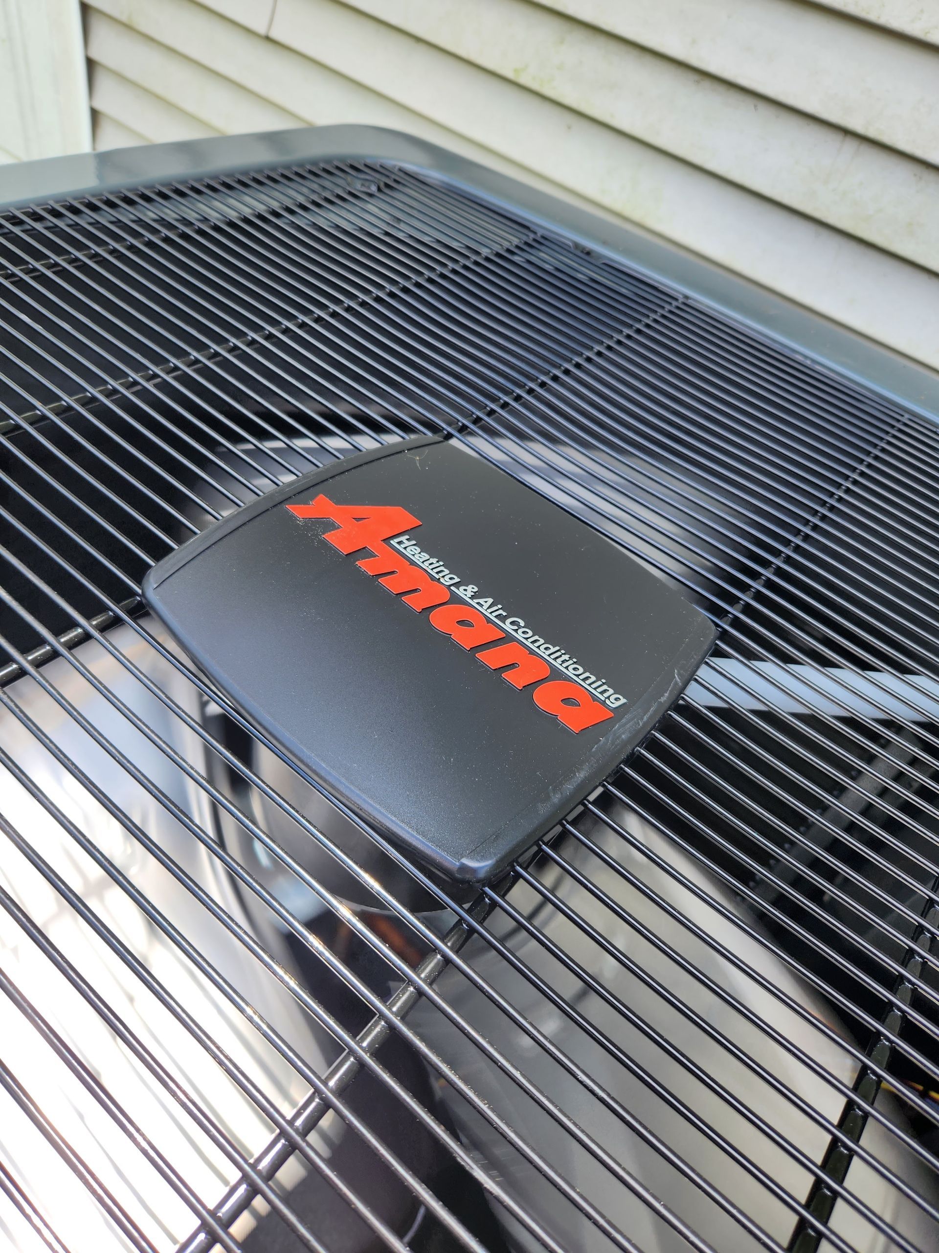 Amana air conditioner unit with black grille and red logo.