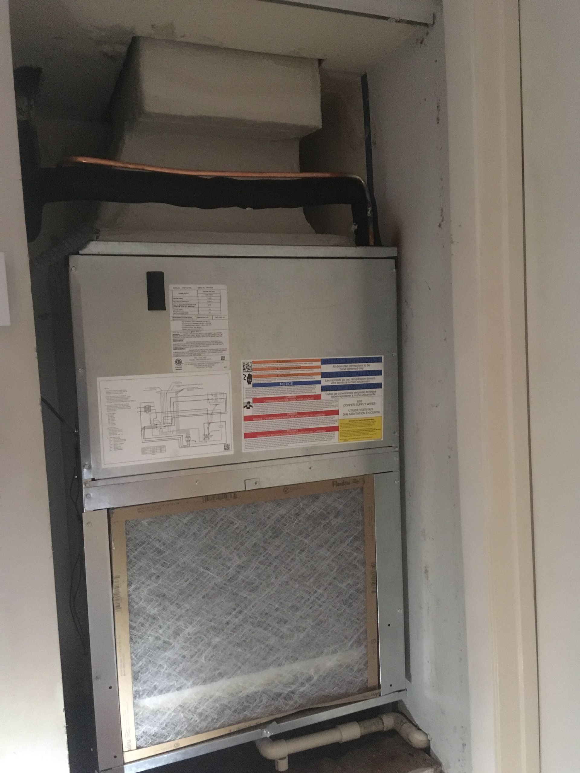 Furnace unit installed in a recessed alcove with a filter and ductwork.