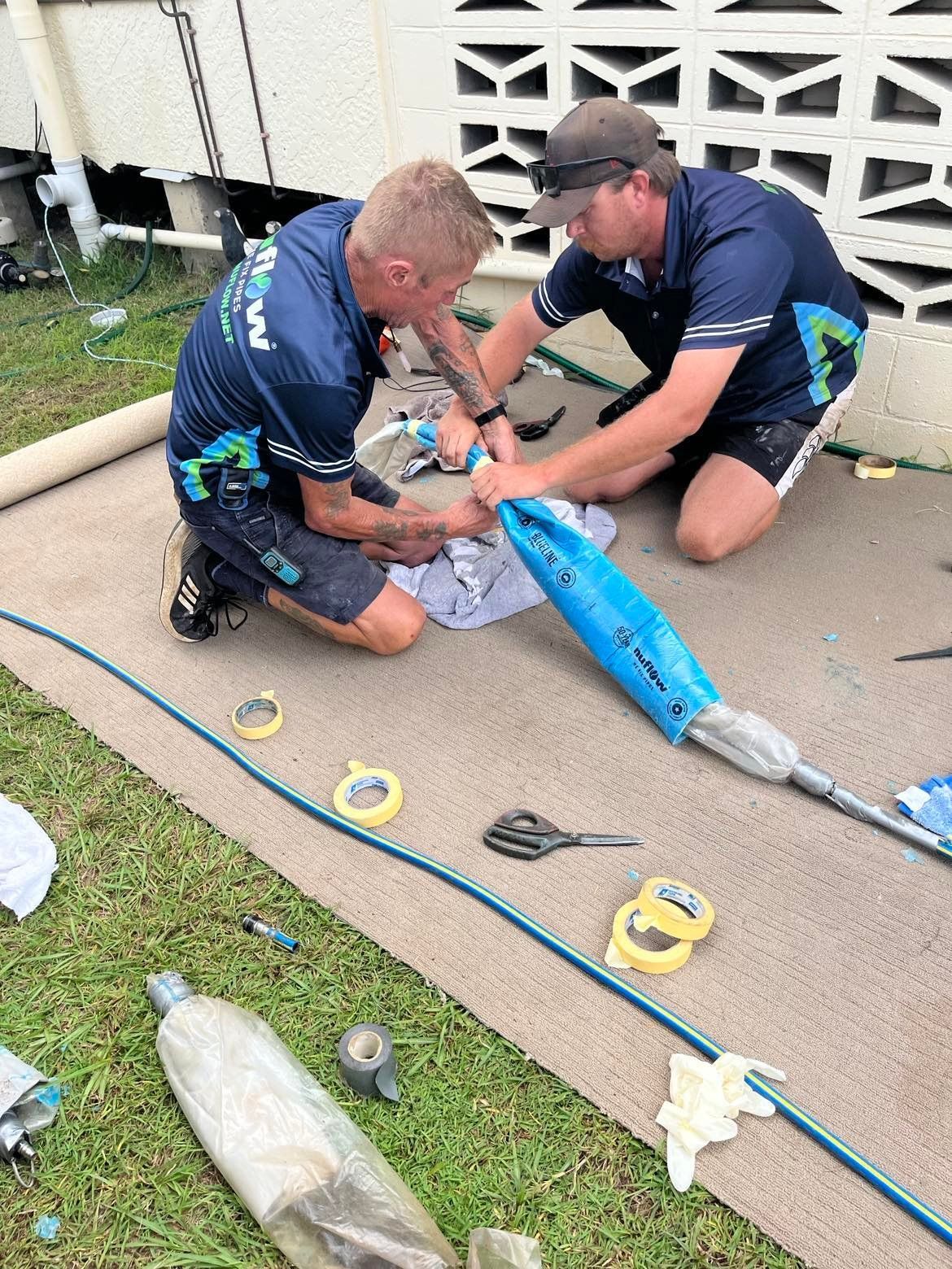 Two Men in Working on A Pipe Outdoors — Nuflow Wide Bay in Bundaberg South, QLD