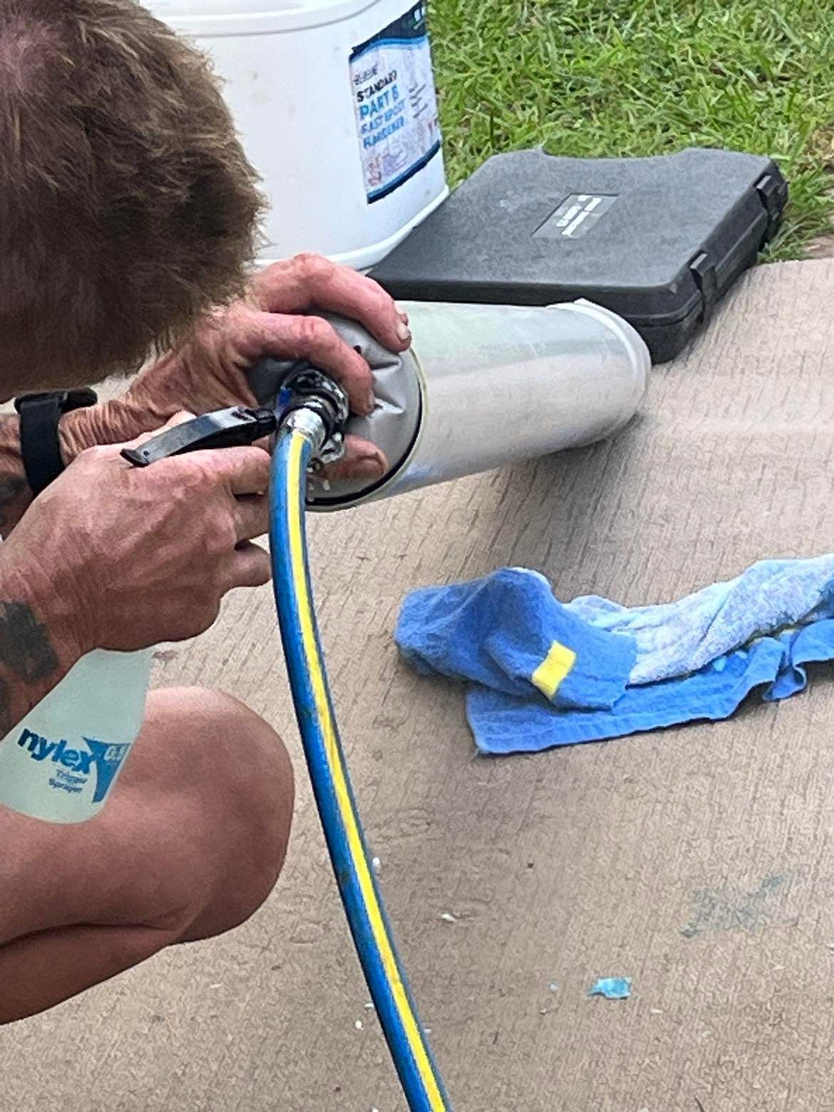 Person using a hose to clean a cylindrical object, outdoor setting. — Nuflow Wide Bay in Hervey Bay, QLD