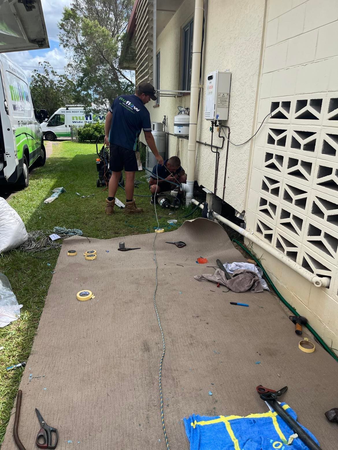Two Plumbers Working on Gas Pipes Beside a Building — Nuflow Wide Bay in Rainbow Beach, QLD