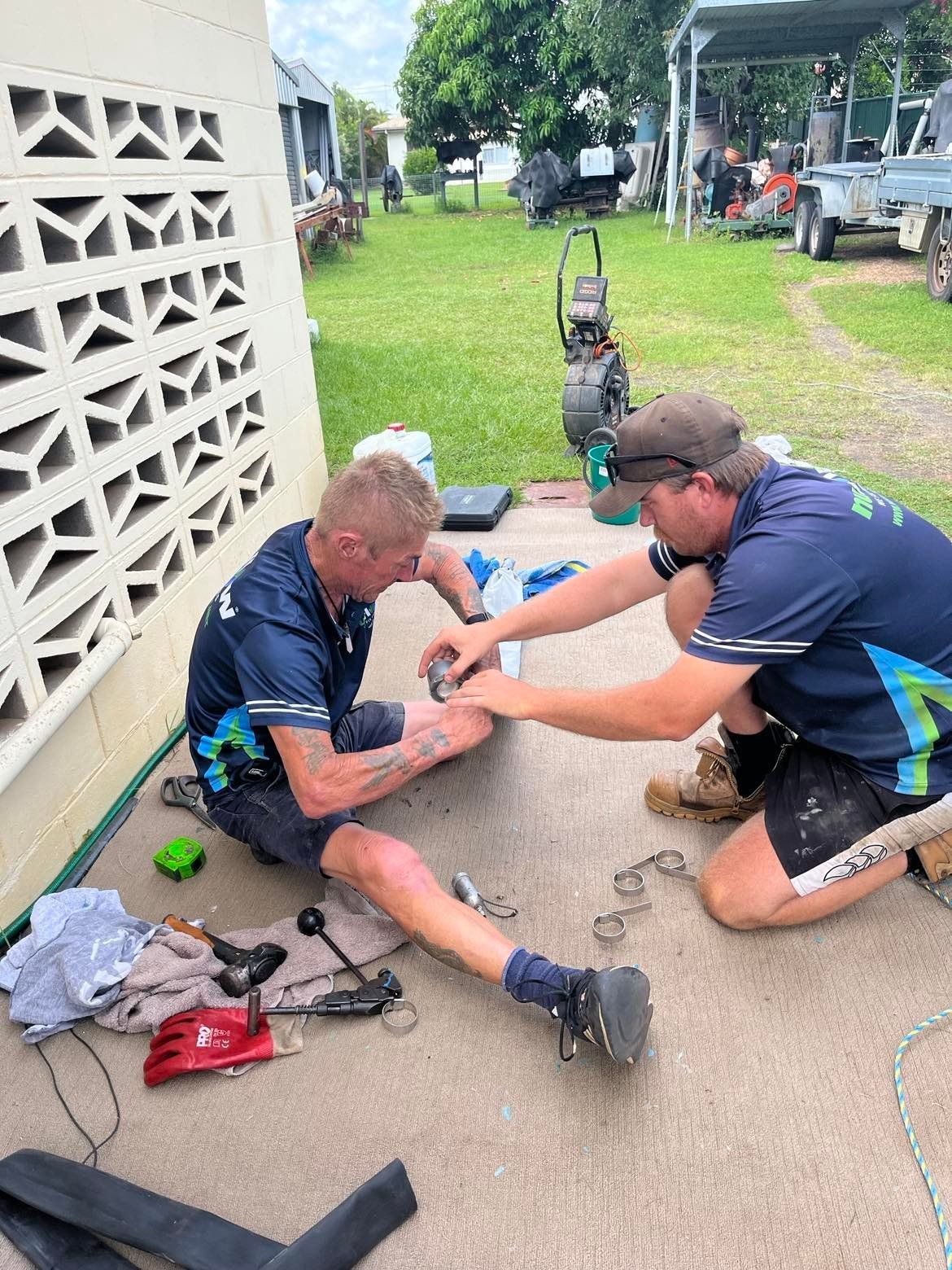 Two Men Working on Equipment Outside — Nuflow Wide Bay in Maryborough, QLD