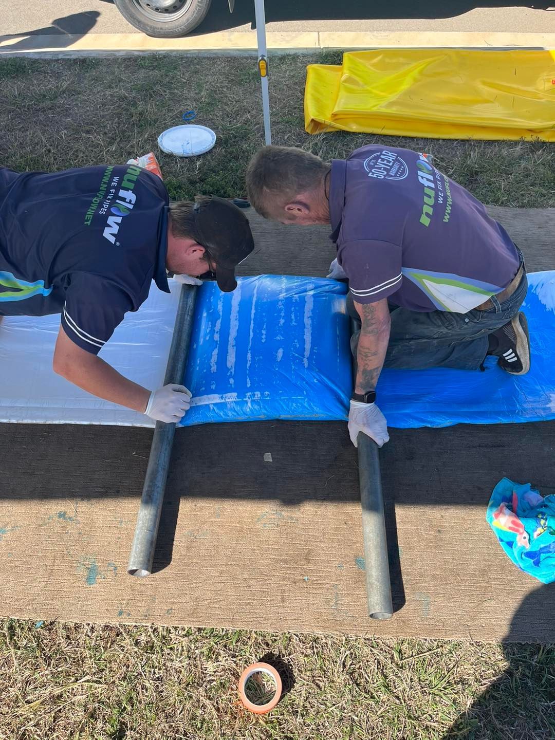 Two Men Working with Tarp and Tubes — Nuflow Wide Bay in Childers, QLD