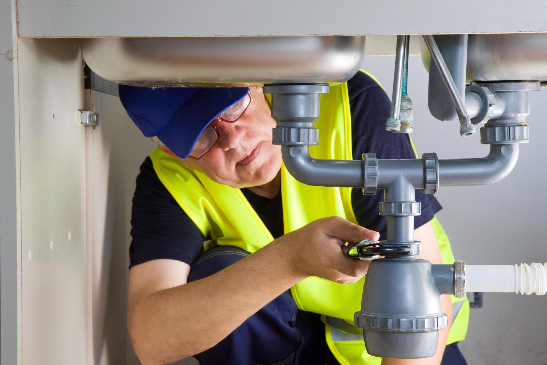 A Plumber Working on Pipes Under a Sink — Nuflow Wide Bay in Childers, QLD