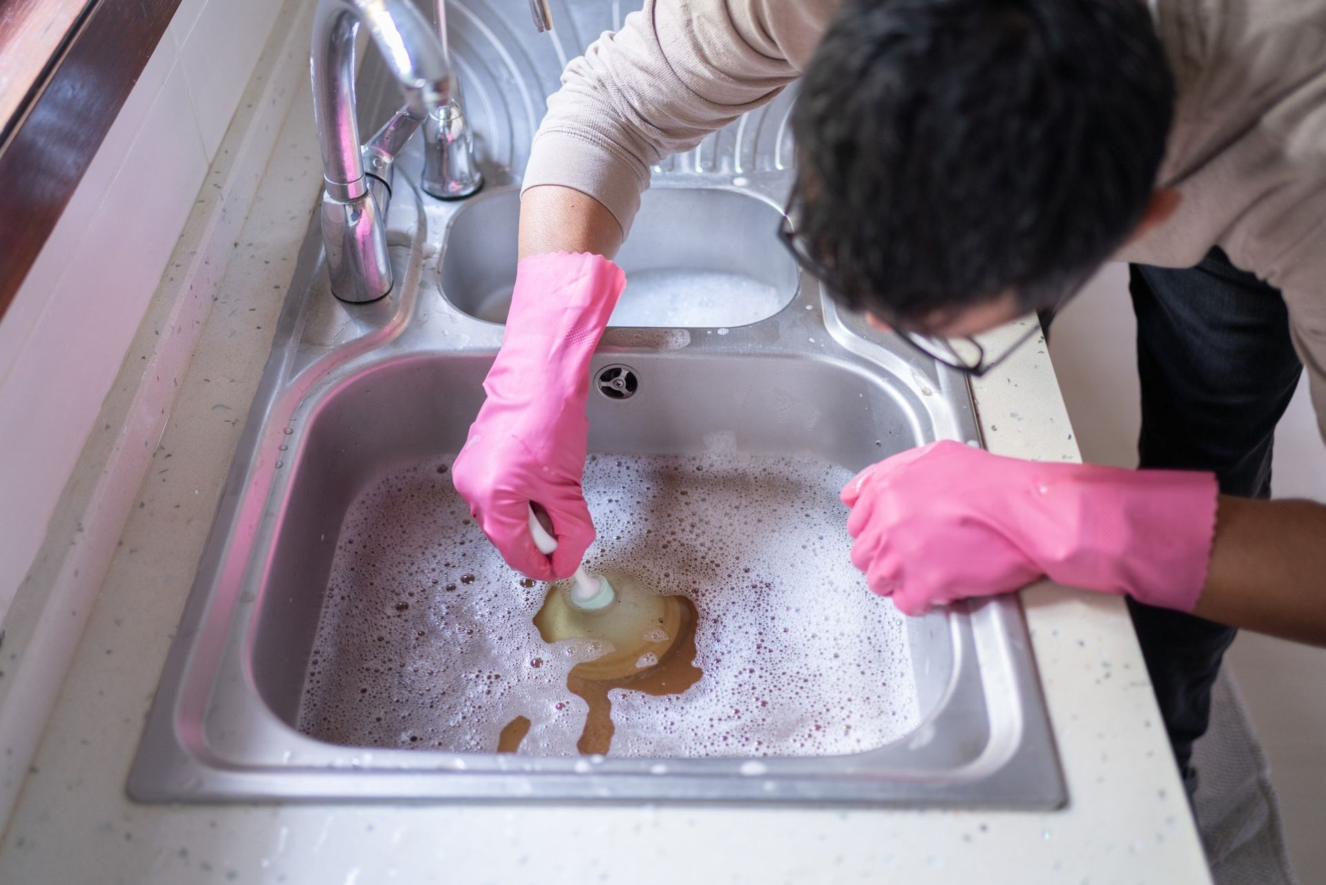 A Person Cleaning a Kitchen Sink — Nuflow Wide Bay in Bundaberg South, QLD