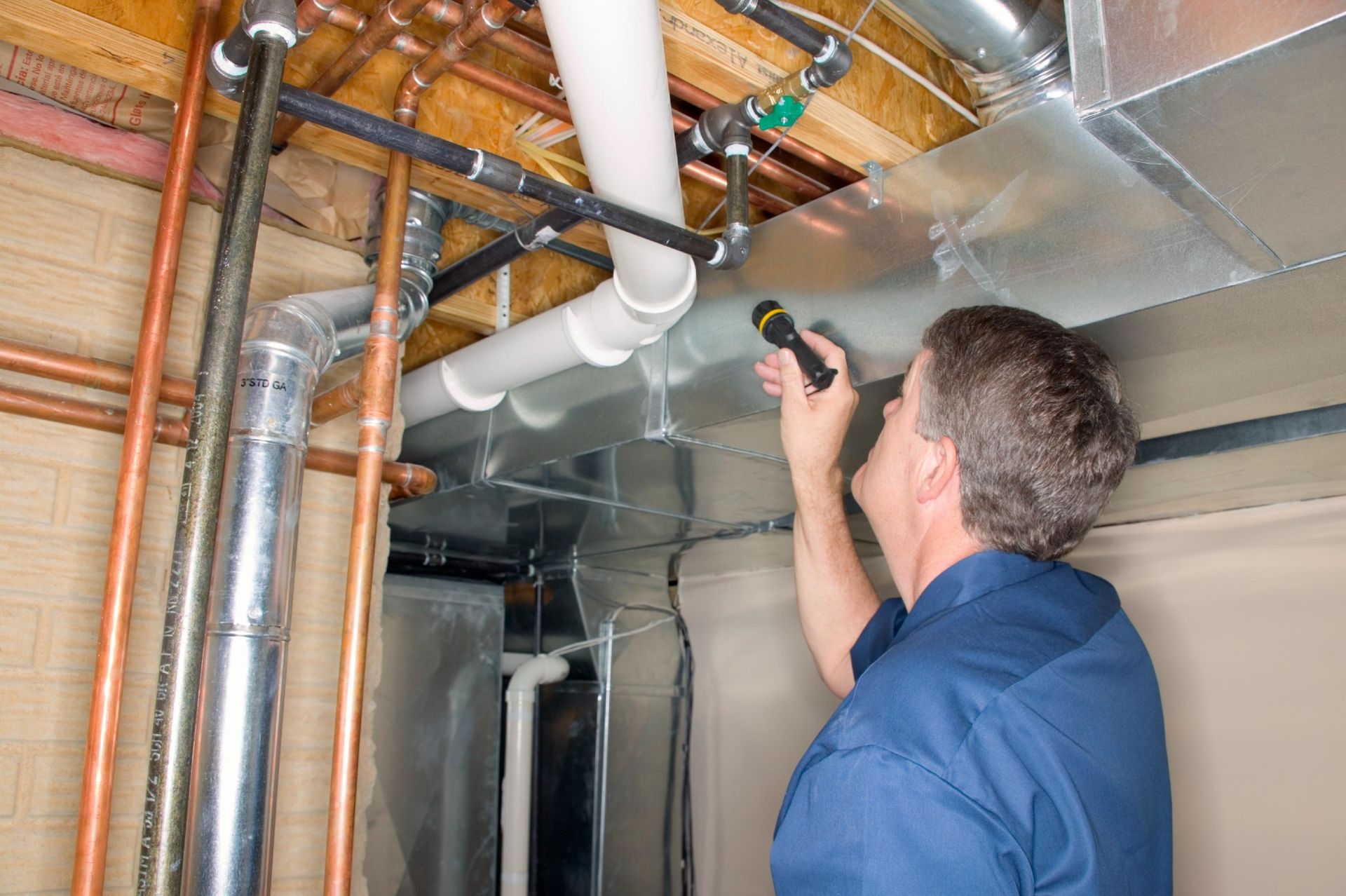 Person inspecting pipes with a flashlight in a basement setting— Nuflow Wide Bay in Bundaberg South, QLD