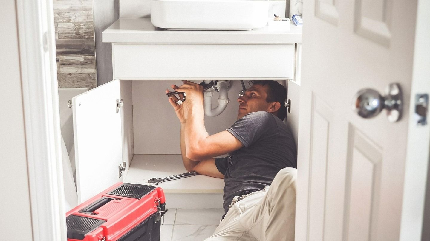 A Man Repairs Pipes Under a Bathroom Sink — Nuflow Wide Bay in Gin Gin, QLD