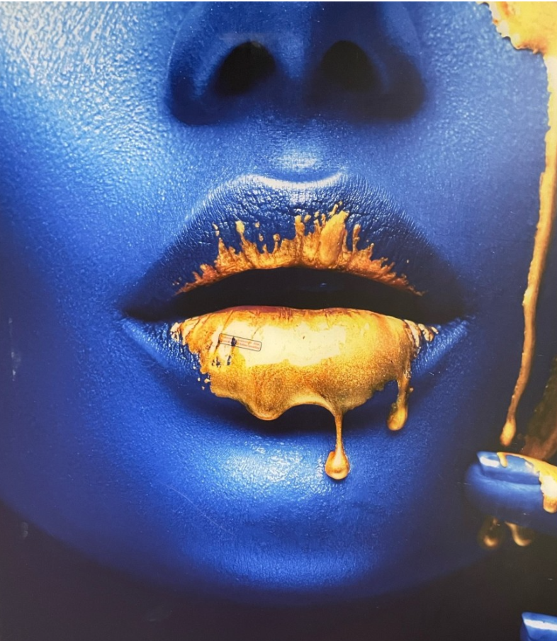 Torso painted metallic blue, gold flecks on face, gold lips.
