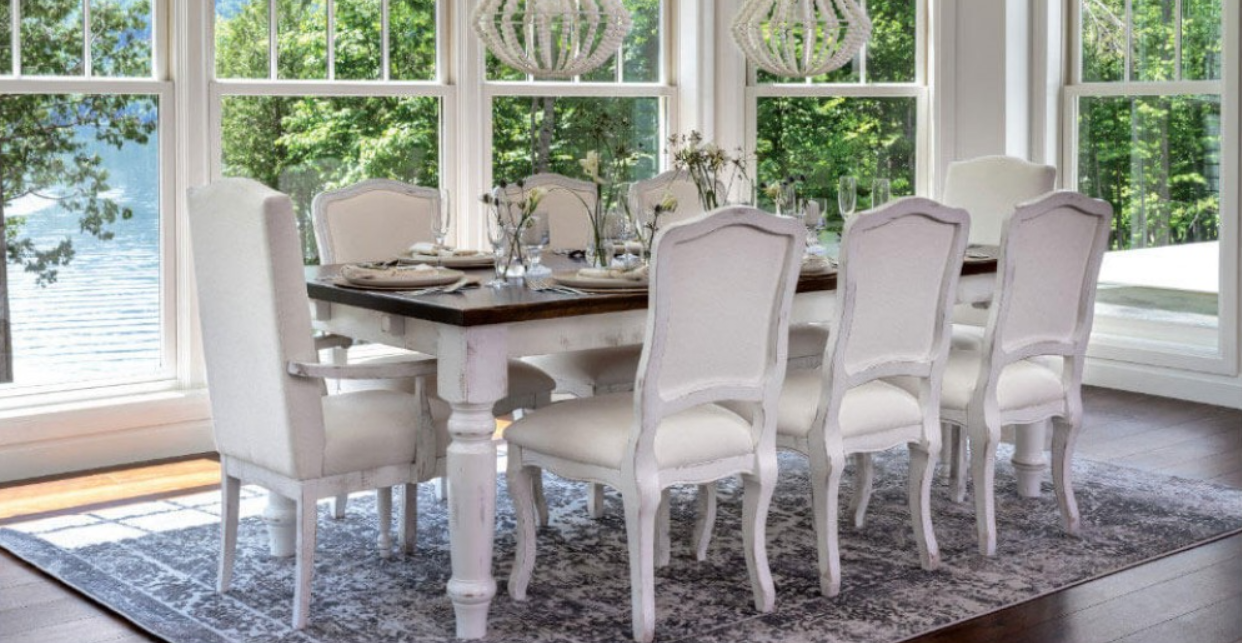Dining room with a white table and chairs, set for a meal, against a window with an outdoor view.