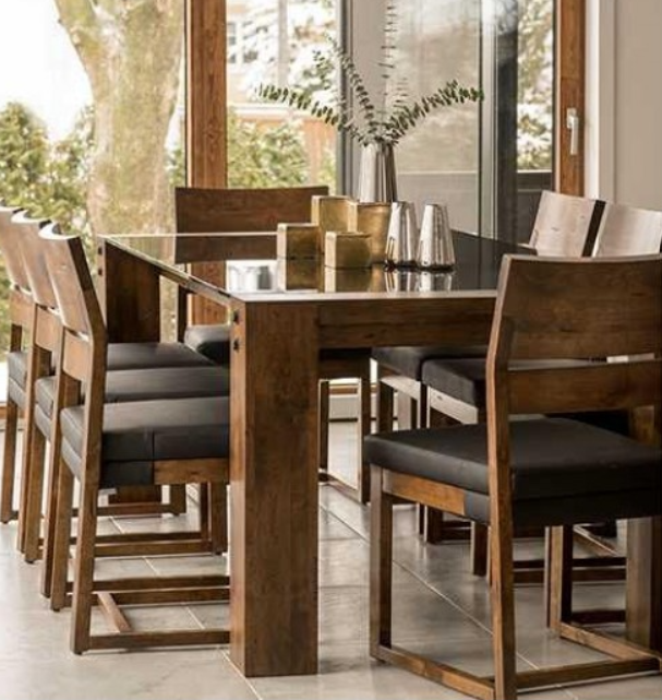 Wooden dining table with eight chairs, black cushions, in front of a window.