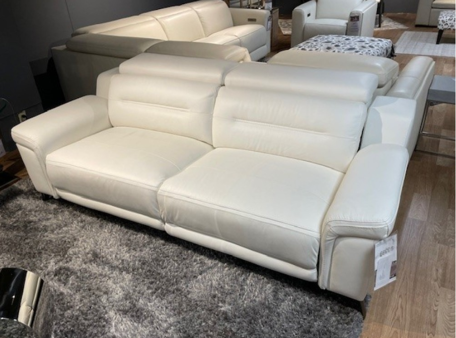 White leather armchair with headrest and armrests, sitting on a hardwood floor.