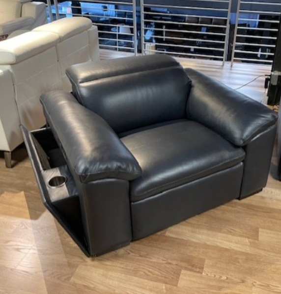 Black leather loveseat indoors, with a floral pattern ottoman in front.