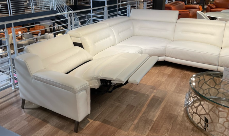 White leather sectional sofa with a glass coffee table in a showroom.