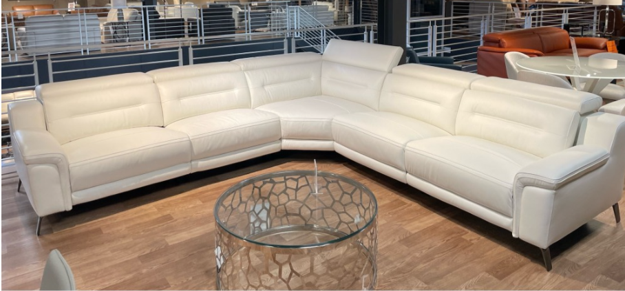 White leather sectional sofa with a glass coffee table in a showroom.