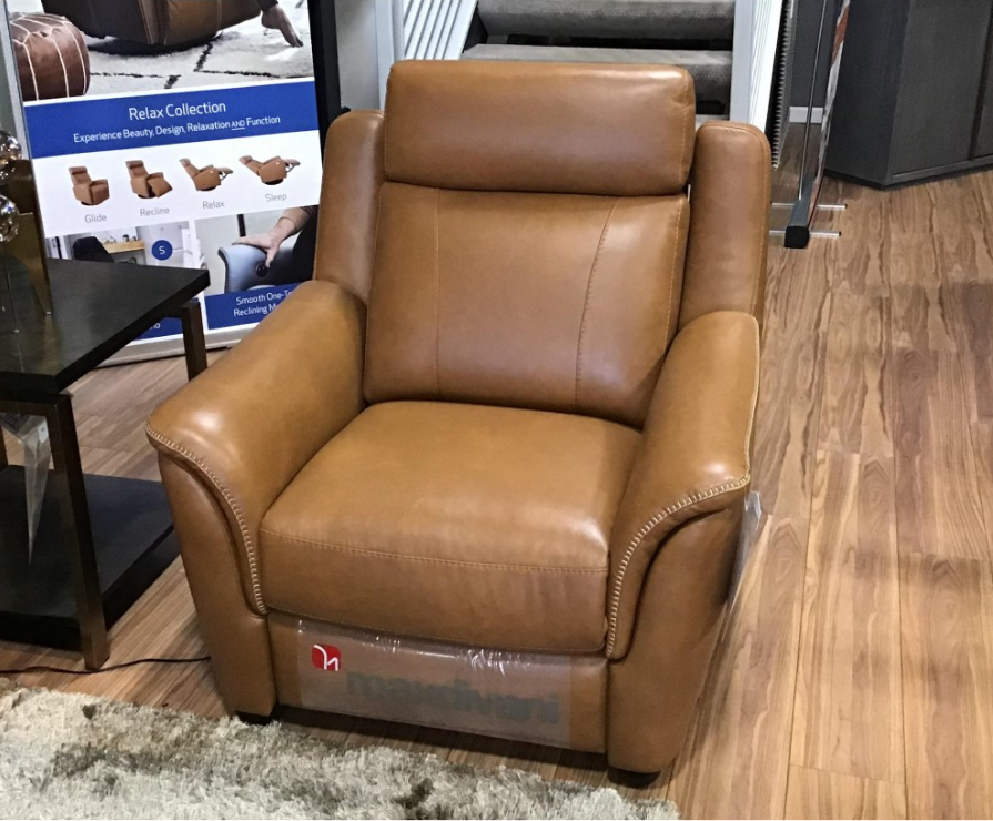 Brown leather recliner chair with footrest extended in a store setting.