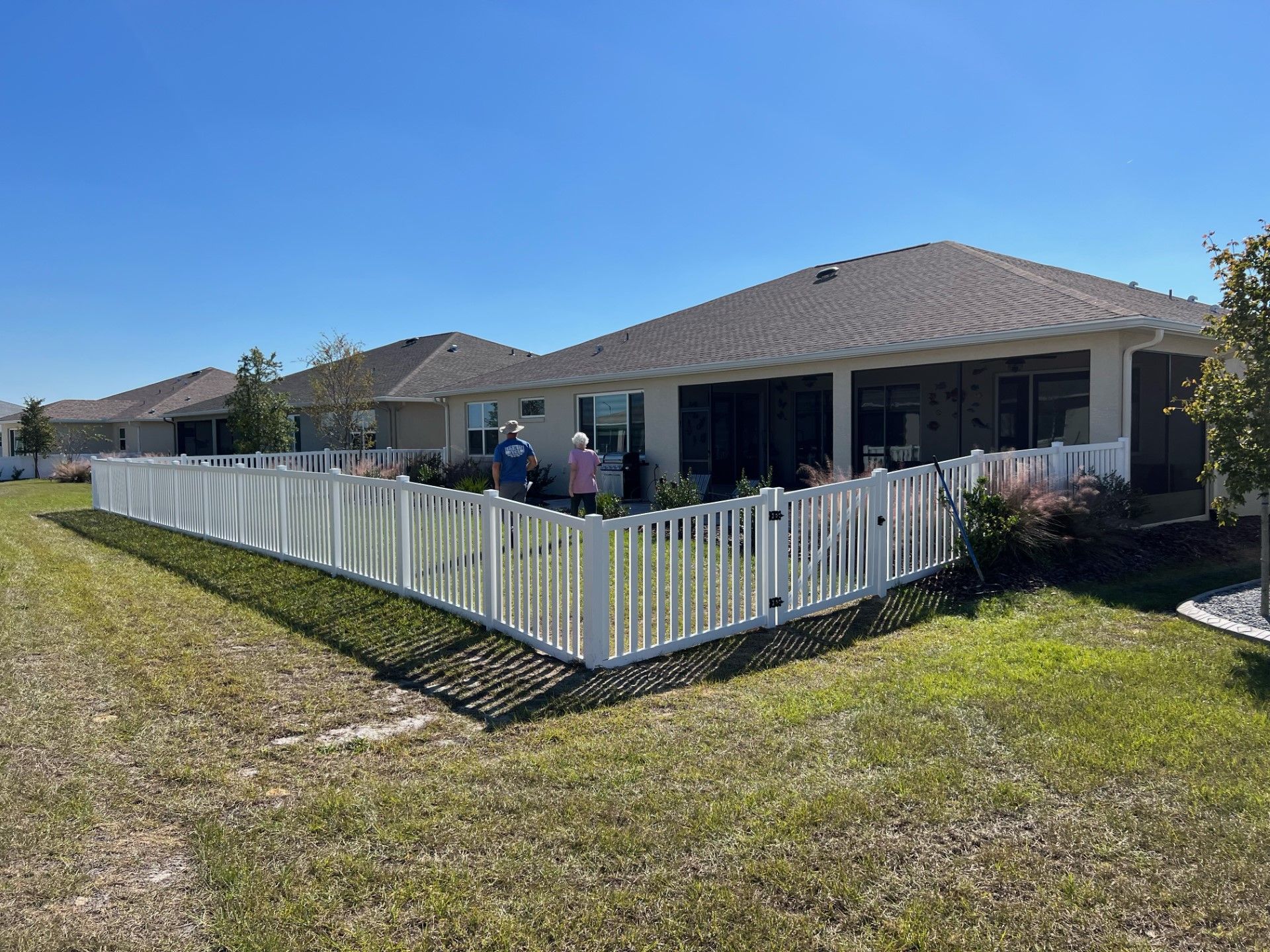 Corner view of a short white vinyl residential fence installation