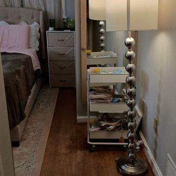 A bedroom with a bed , nightstand , lamp and dresser.