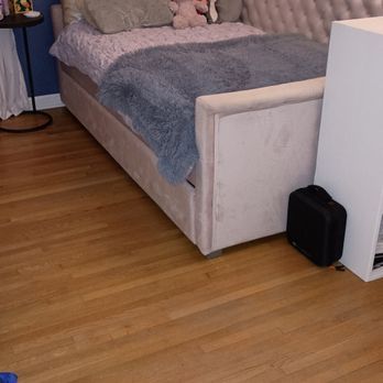 A bedroom with hardwood floors , a bed , a couch and a briefcase.