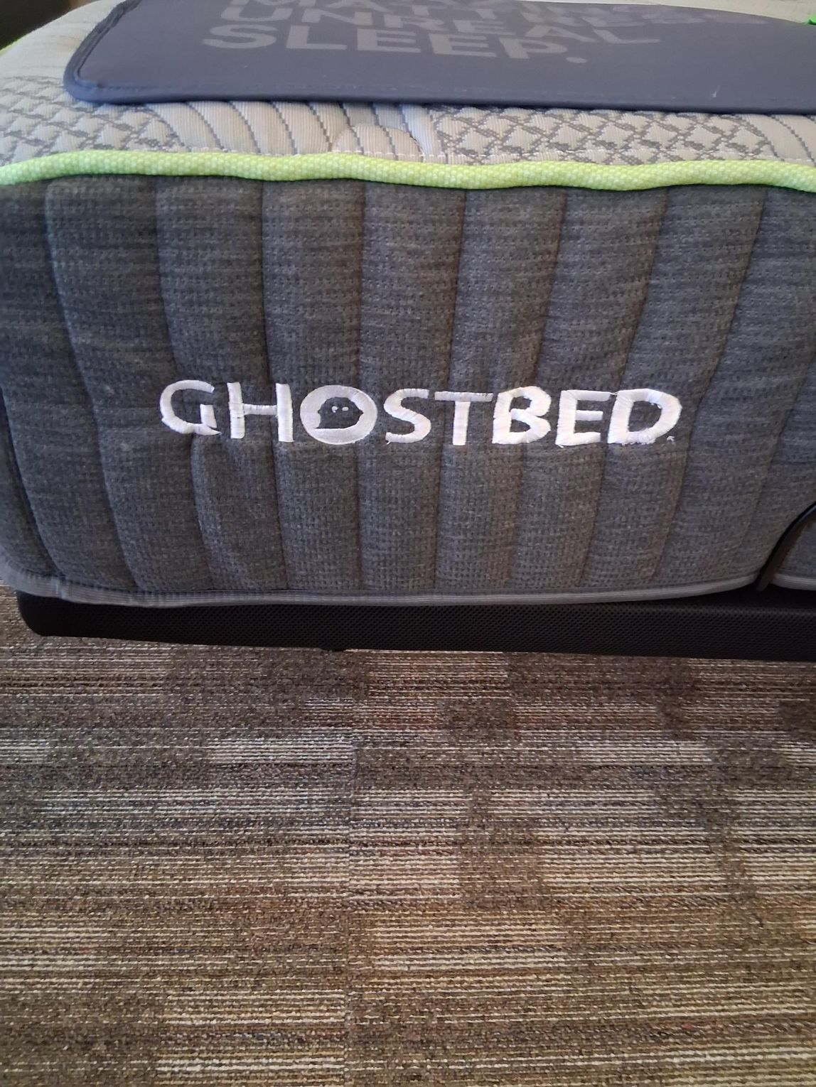 Close-up of a GhostBed mattress with grey sides, neon green trim, and the brand name in white.