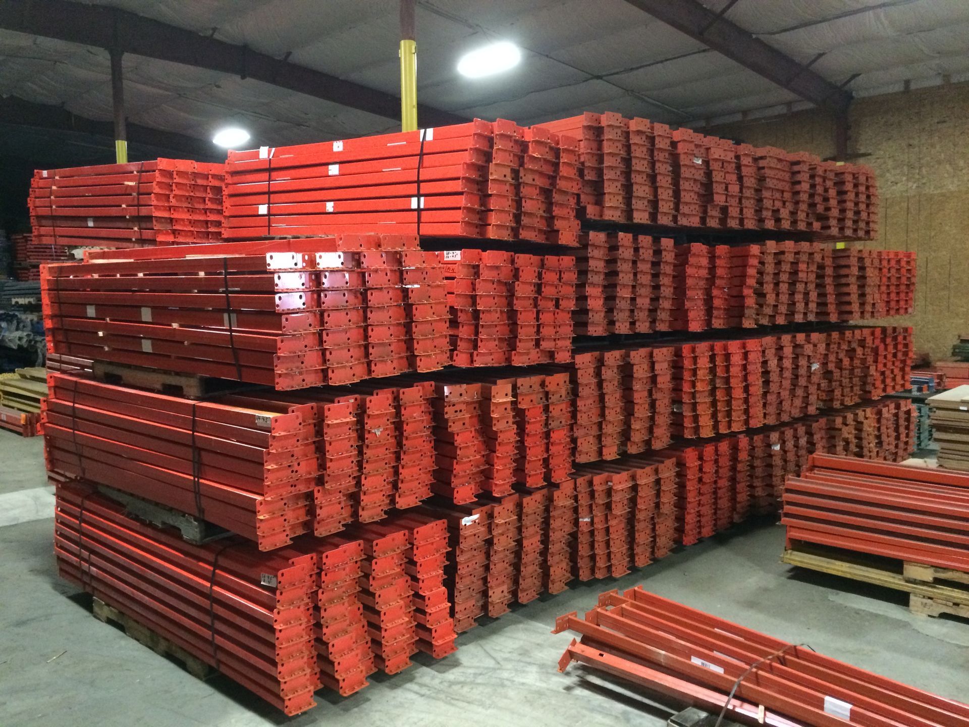 A bunch of red pallets are stacked on top of each other in a warehouse.
