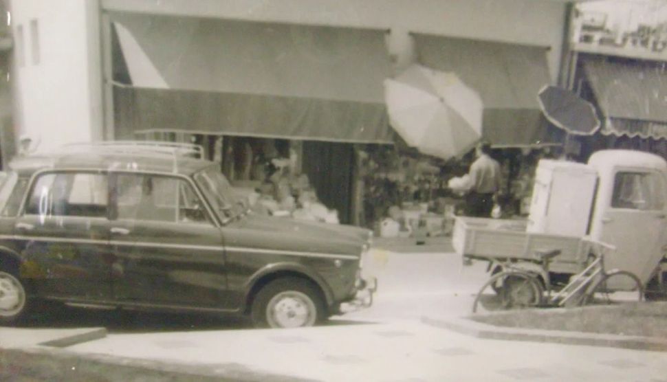 Una foto in bianco e nero di un'auto parcheggiata davanti a un edificio.