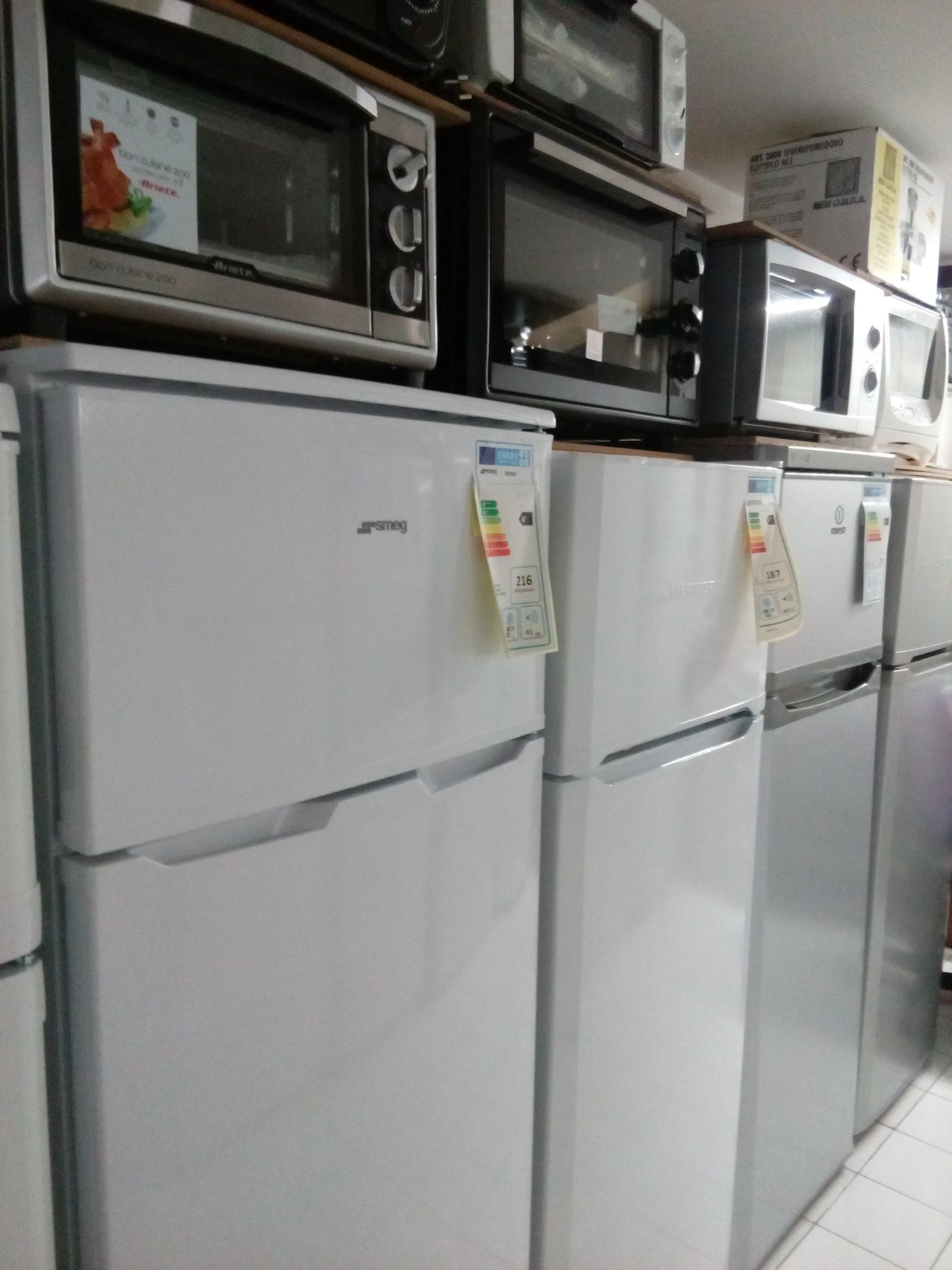 Una fila di frigoriferi e forni a microonde sono allineati in una stanza.