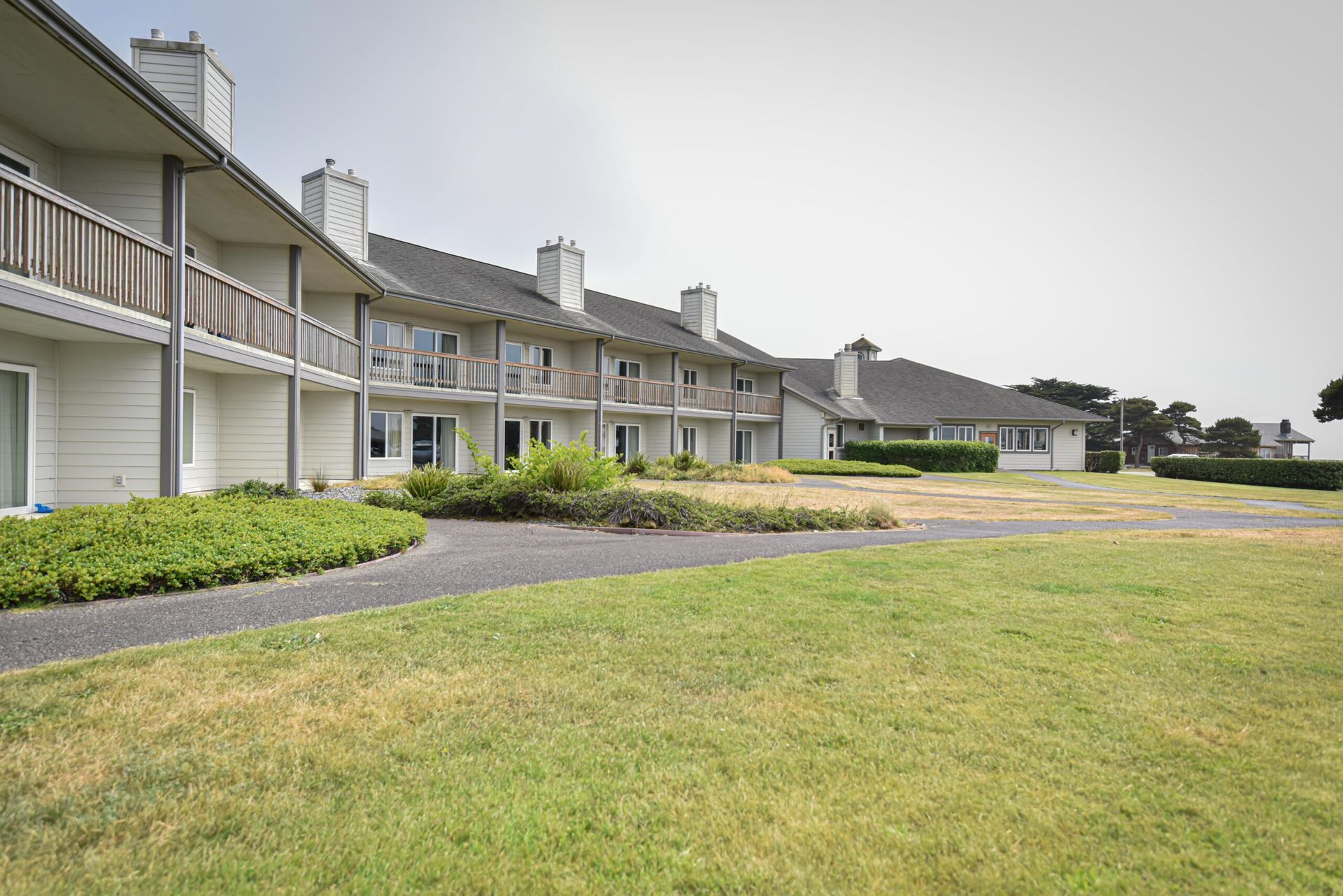 Row of light-colored buildings with balconies, chimneys, and a grassy yard.