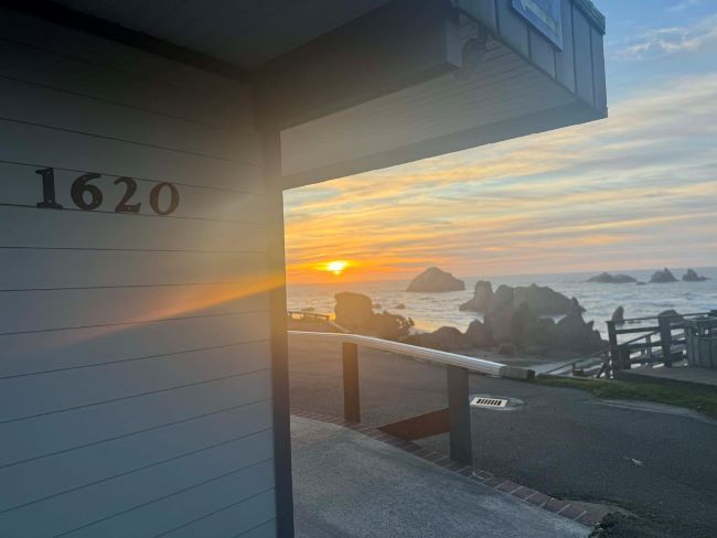 Sunset over ocean viewed from under a building labeled 