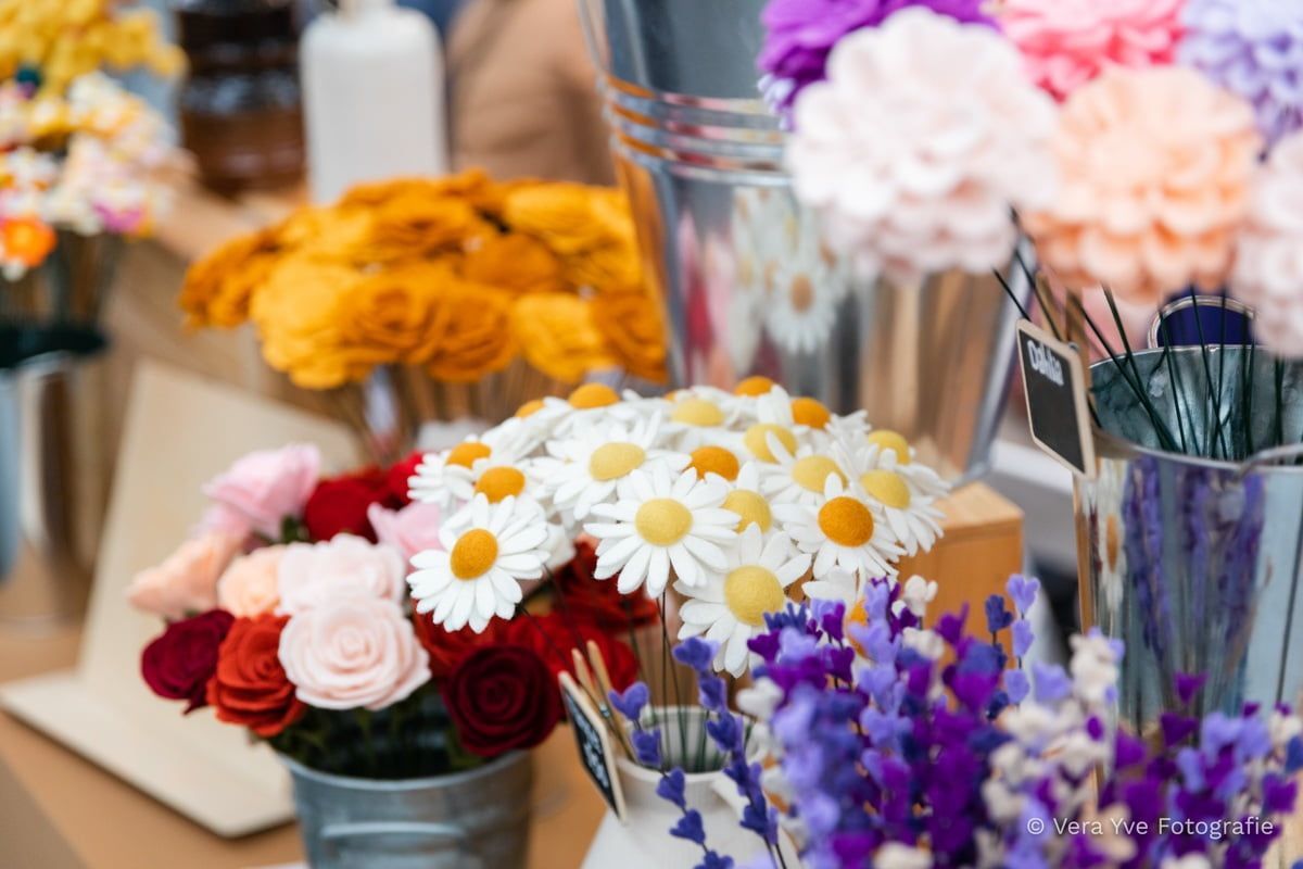 Een bos viltbloemen staat in emmers op een tafel.